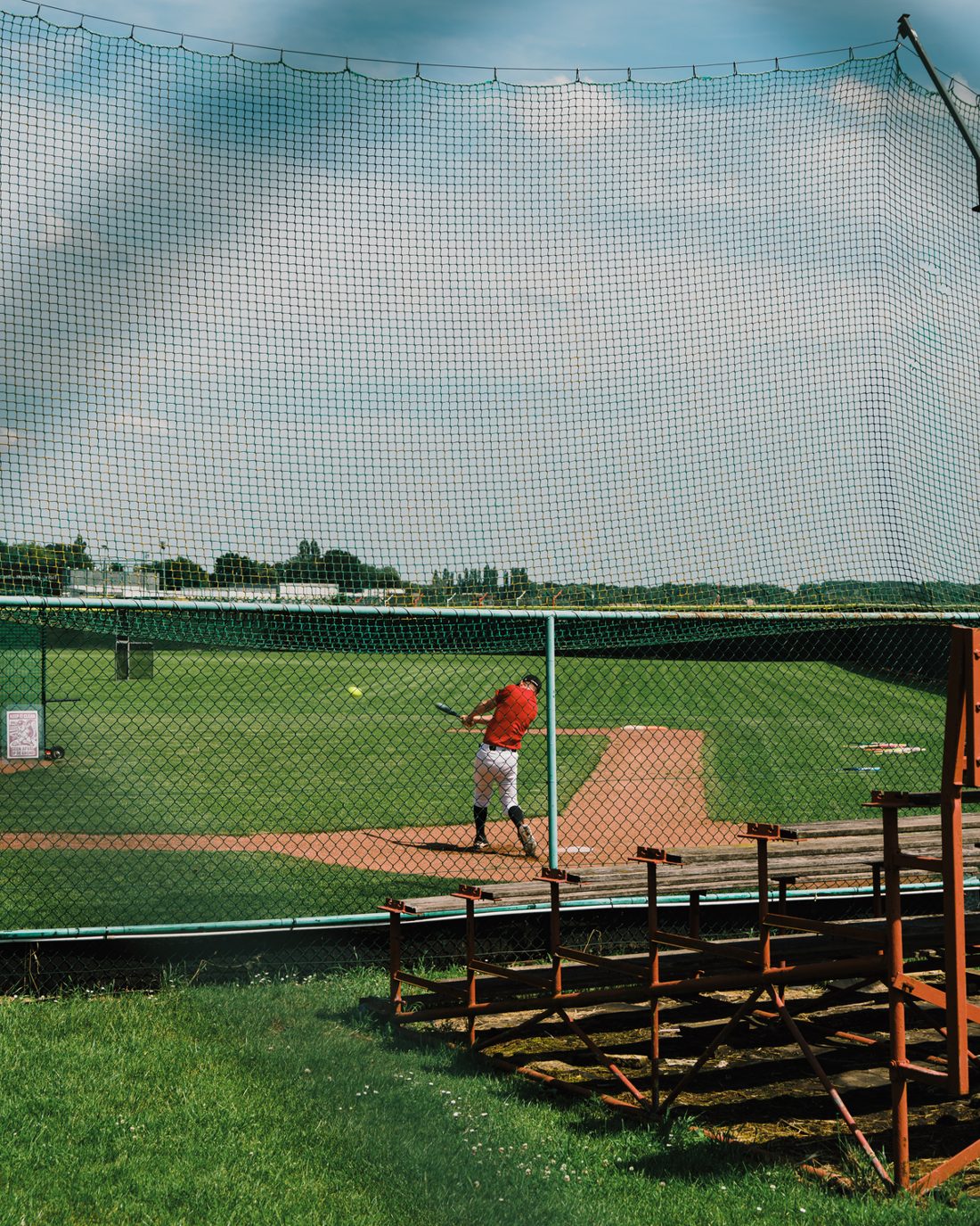 A batter swinging in a batting cage
